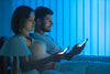 man and woman in bed watching their phones